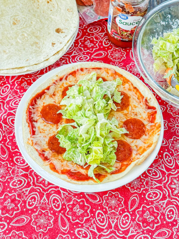 Pizza tortilla topped with Caesar salad before being rolled into a wrap