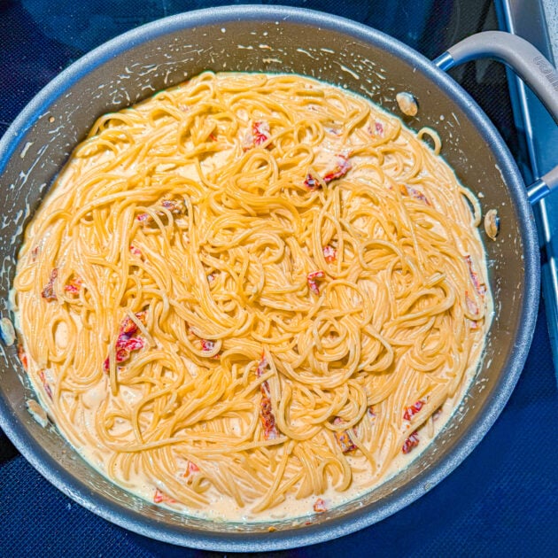 One-pan creamy sun-dried tomato pasta cooking in a large skillet