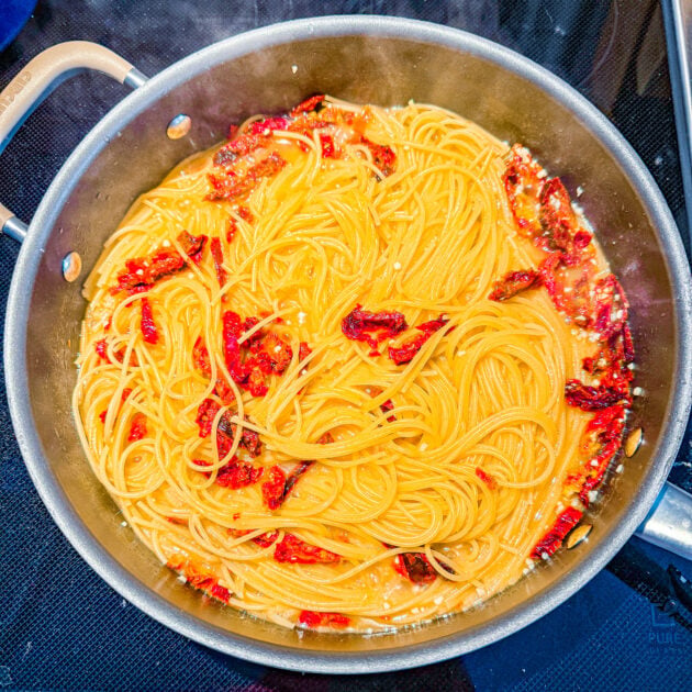 Pasta cooking in chicken broth with garlic, basil, and sun-dried tomatoes