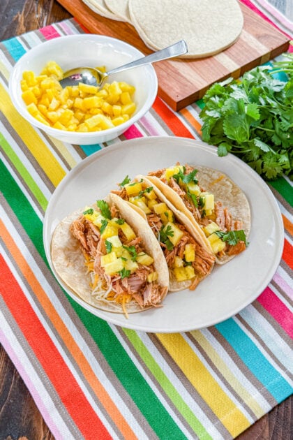 Tender al pastor-style pork cooked in a slow cooker with enchilada sauce, onion, garlic, and pineapple juice