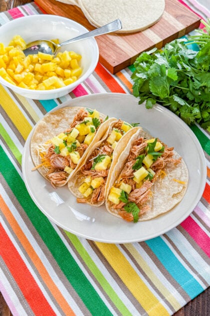 Overhead view of slow cooker tacos al pastor served with pineapple, cilantro, and lime