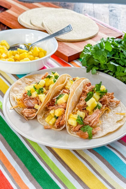 Warm corn tortillas filled with shredded pork and topped with fresh pineapple and cilantro