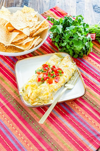 chicken enchiladas covered with creamy green enchilada sauce and shredded cheese before baking