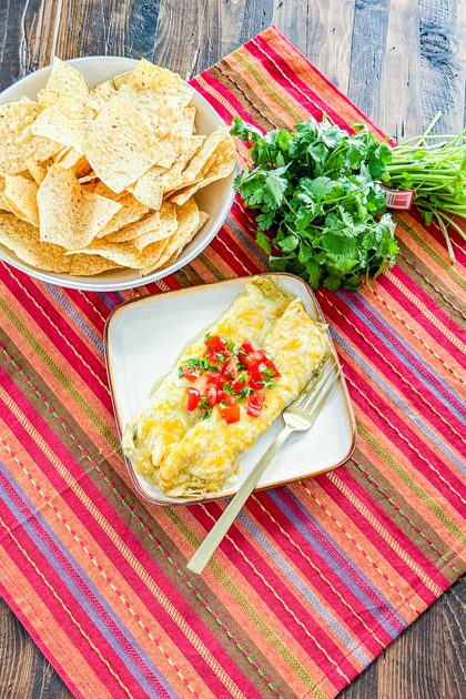 creamy green chile chicken enchiladas covered with green enchilada cream sauce and melted cheese