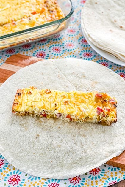 Flour tortilla topped with ham, egg, cheese, and hash brown filling for a breakfast burrito