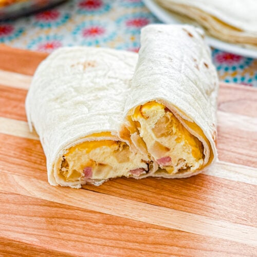 Sliced breakfast burrito showing baked egg, ham, cheese, and hash brown filling