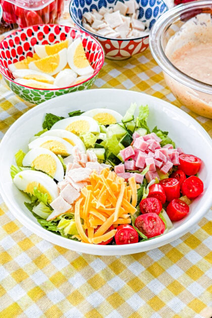 Easy chef salad with ham, turkey, hard-boiled eggs, cheddar cheese, tomatoes, cucumber, and homemade Thousand Island dressing
