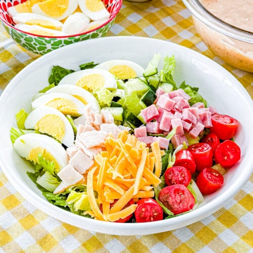 Close-up of chef salad topped with ham, turkey, eggs, cheese, tomatoes, and cucumber