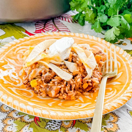 One-pan beef enchilada rice skillet with ground beef, rice, corn, tortillas, and melted cheddar cheese.