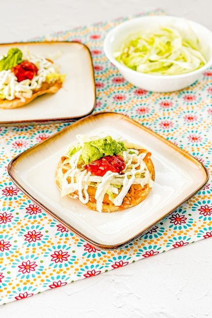 Crispy bean tostada served with cheese, lettuce, sour cream, guacamole, and salsa