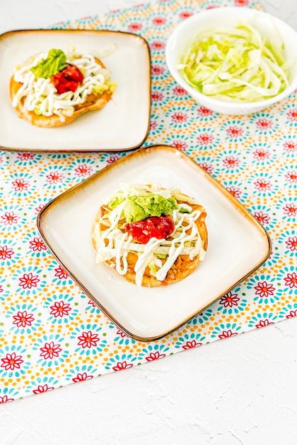 Oven-baked tostadas topped with beans, cheese, lettuce, sour cream, guacamole, and salsa