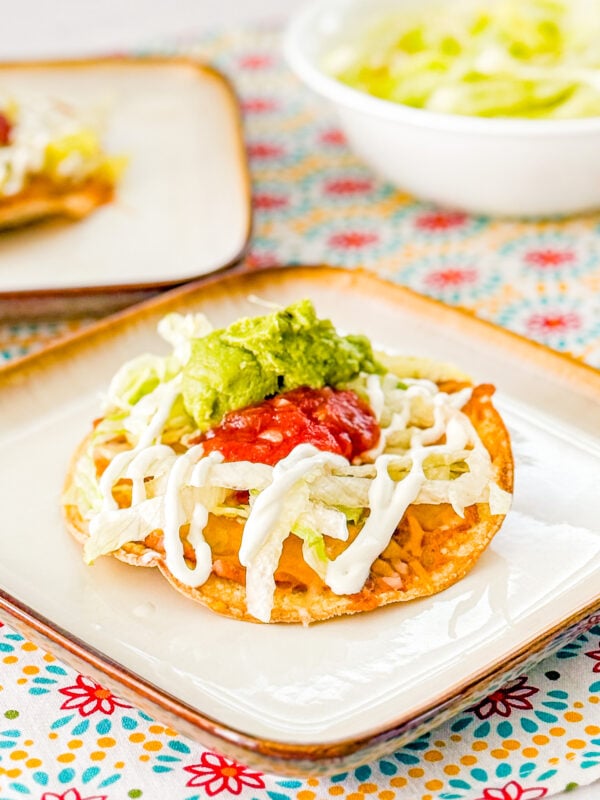10 Minute Oven-Baked Tostadas topped with refried beans, cheese, lettuce, sour cream, guacamole, and salsa
