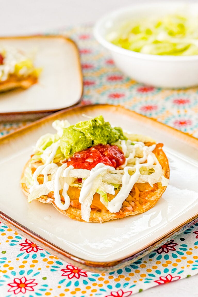10 Minute Oven-Baked Tostadas topped with refried beans, cheese, lettuce, sour cream, guacamole, and salsa