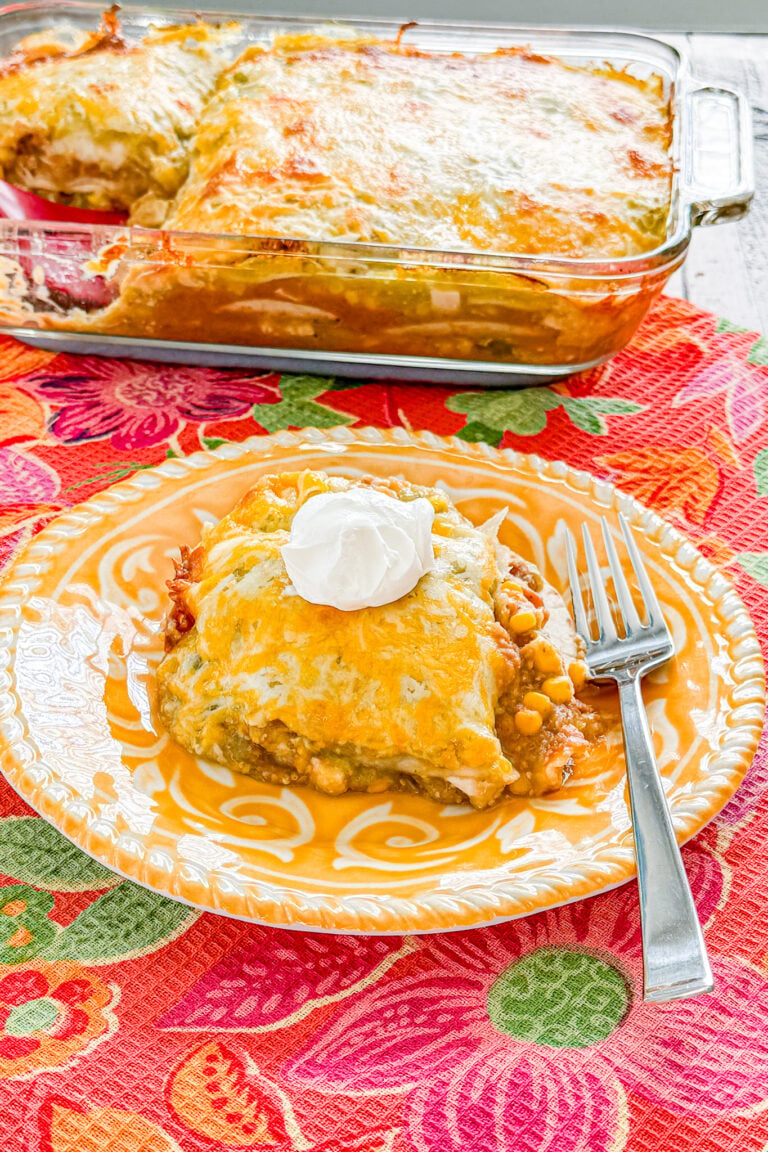 Chicken taco casserole with chicken, refried beans, corn, green salsa, tortillas, and melted cheese