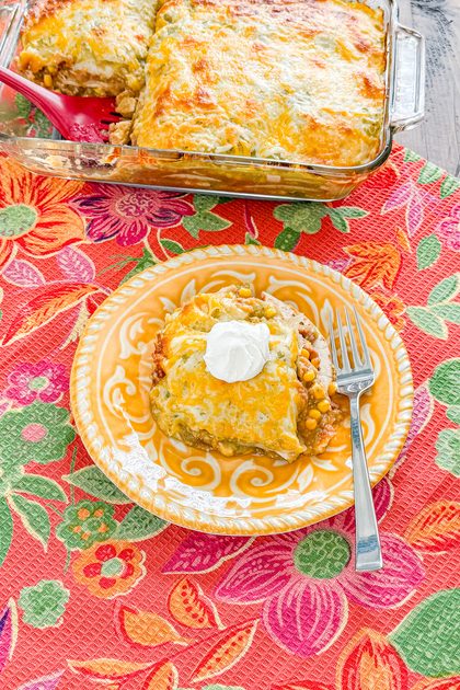 Slice of chicken taco casserole showing layers of tortillas, chicken, beans, corn, salsa, and cheese