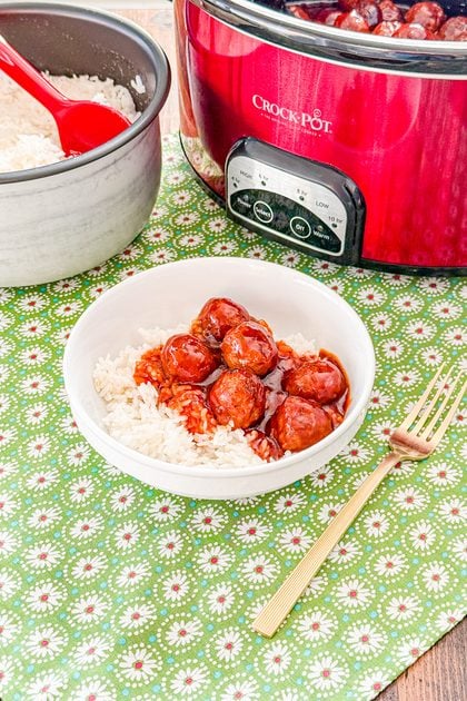 Crockpot cola meatballs served over cooked white rice with extra barbecue sauce
