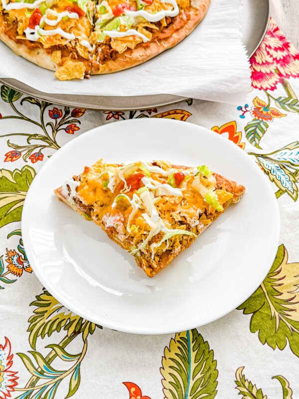 Easy Loaded Taco Pizza with ground beef, refried beans, cheese, lettuce, sour cream, and salsa