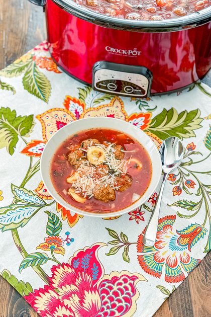 Bowl of slow cooker meatball tortellini soup topped with shredded Parmesan