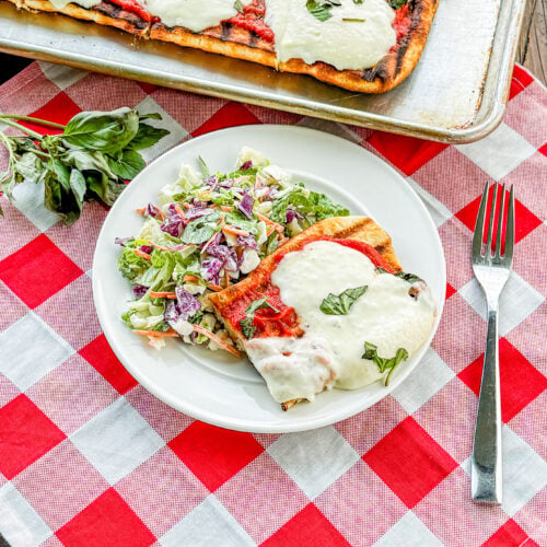 Grilled pizza crust topped with tomato sauce and fresh mozzarella