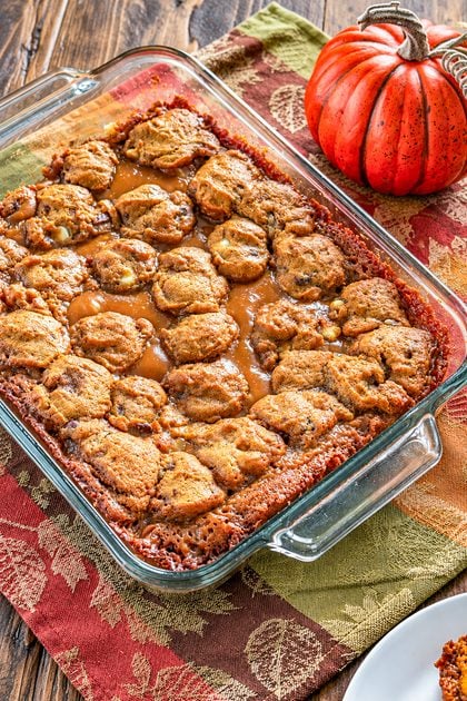 Close-up of pumpkin caramel bars in a baking dish with gooey caramel filling and golden topping