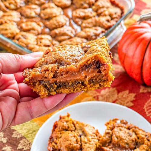Hand holding a gooey loaded pumpkin caramel bar
