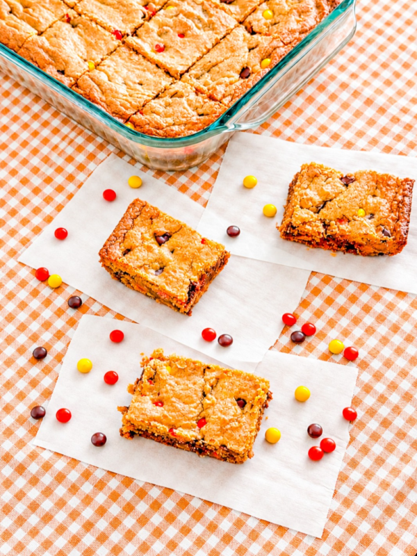 Peanut butter blondies cut into squares with chocolate chips and Reese’s Pieces