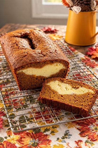 Freshly baked pumpkin cream cheese bread loaf on a cooling rack with a slice cut from the loaf